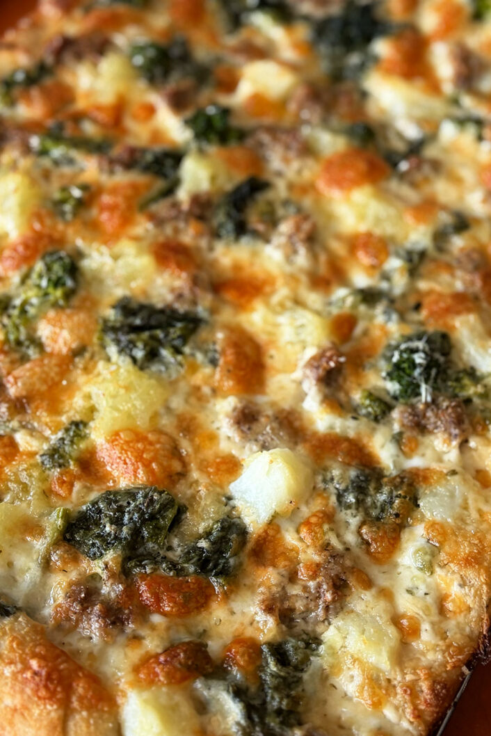 Pizza bianca avec sauce Alfredo, saucisses italiennes, pommes de terre et rapini