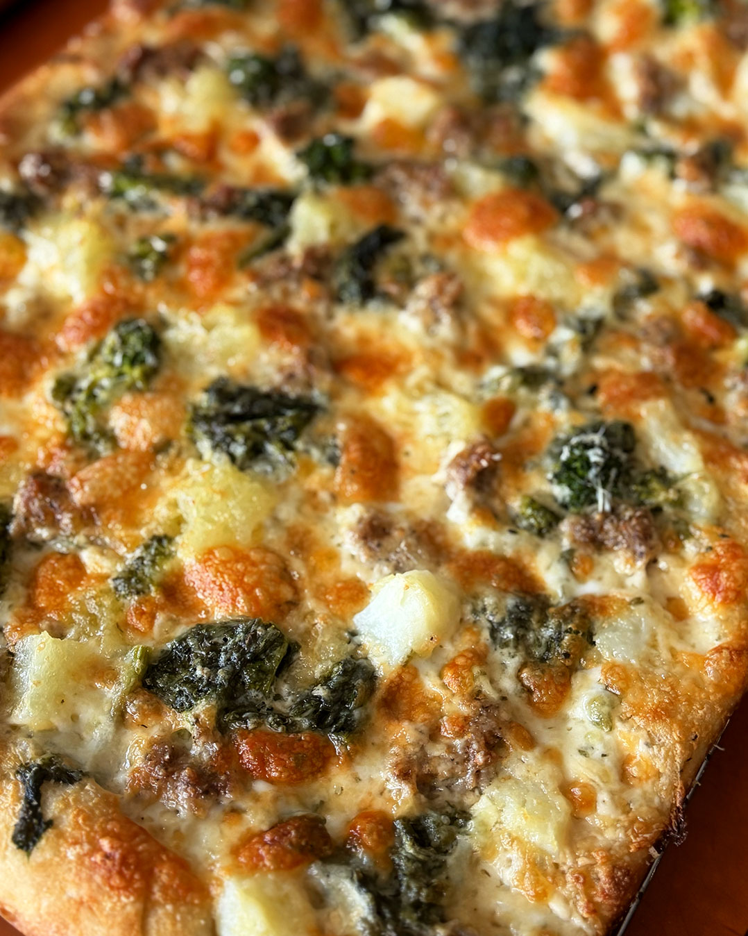 Pizza bianca avec sauce Alfredo, saucisses italiennes, pommes de terre et rapini