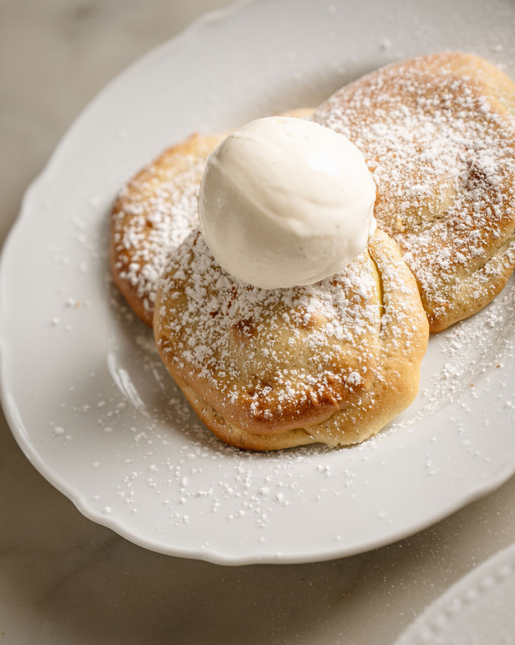 Beignets aux pommes cuits au four, saupoudrés de sucre à glace et garnis d'une boule de gelato à la vanille