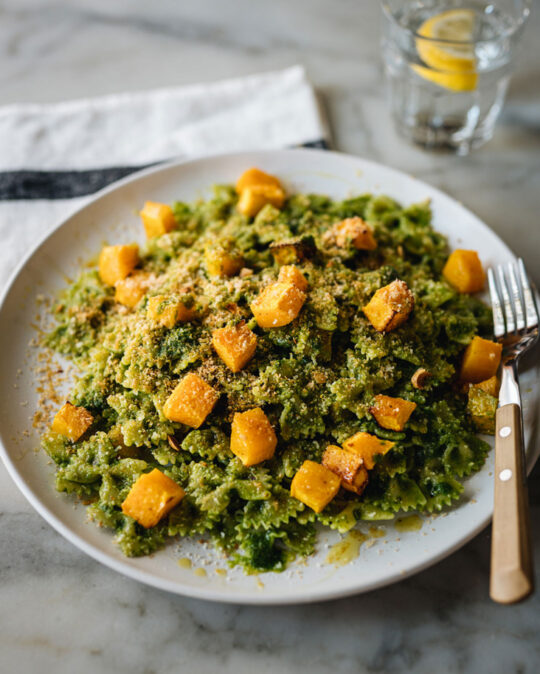 Une assiette de pâtes farfalle avec pesto de kale et cubes de courge rôtie